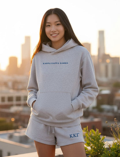 Individual wearing grey hoodie and matching shorts with Kappa Kappa Gamma text
