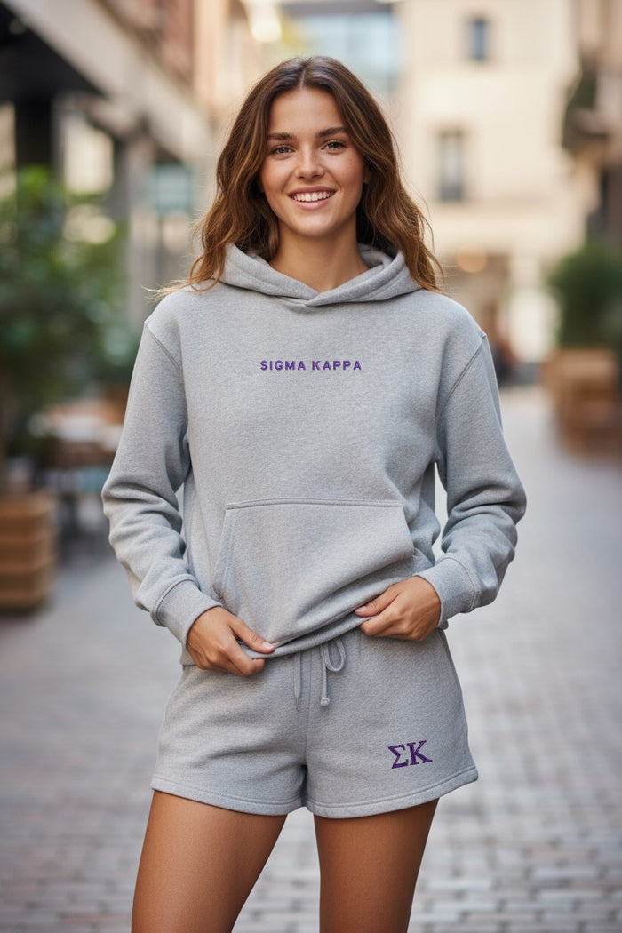 Woman outdoors in gray Sigma Kappa hoodie and matching shorts with Greek letters