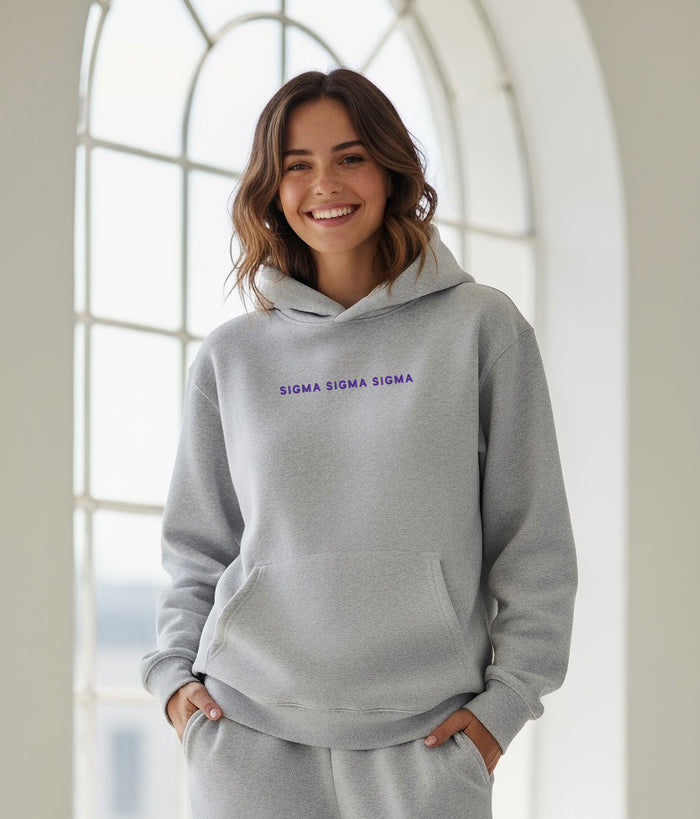 Woman smiling indoors in gray Sigma Sigma Sigma hoodie