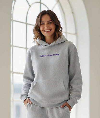 Woman smiling indoors in gray Sigma Sigma Sigma hoodie